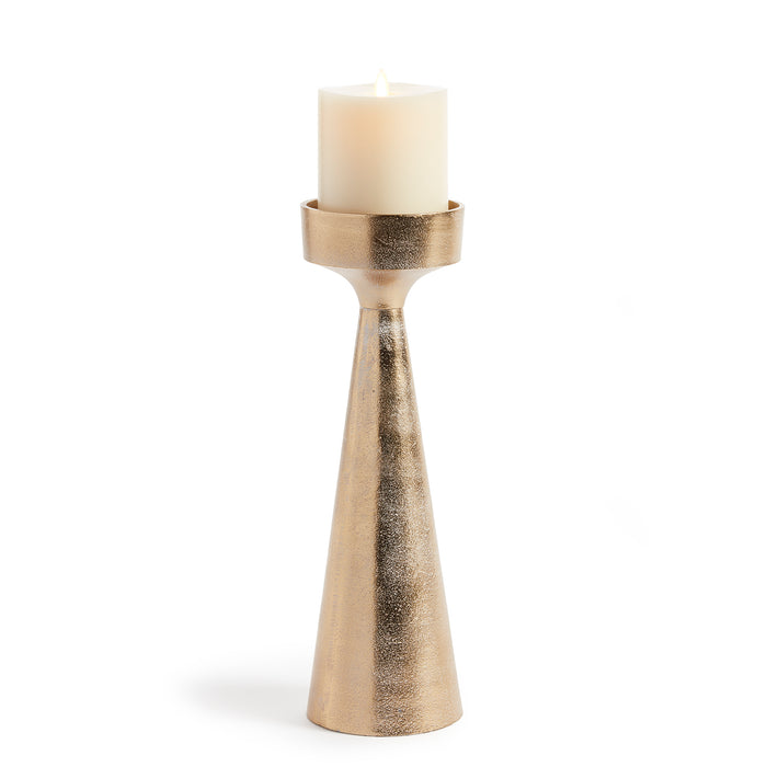 A gold-colored aluminum candle stand with a cylindrical base and a rolled edge, featuring a white ash wash finish and a candle placed on top.