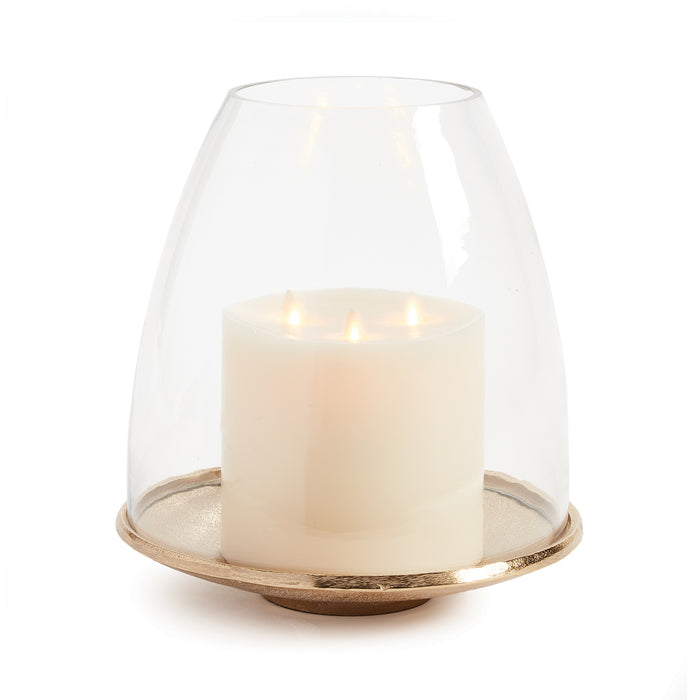 A white candle with a clear glass holder and a gold-colored metal base.