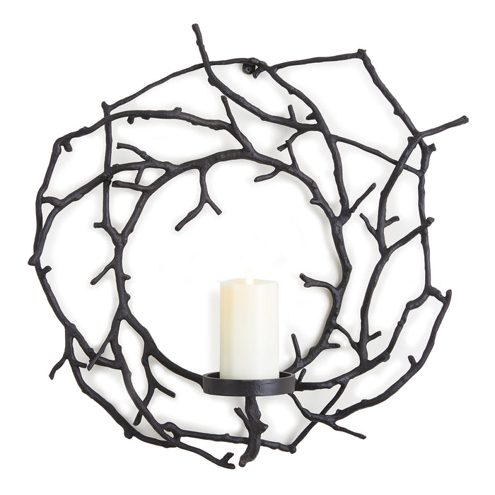 A circular black metal candle holder with a design that resembles branched wood, featuring a candle in the center.