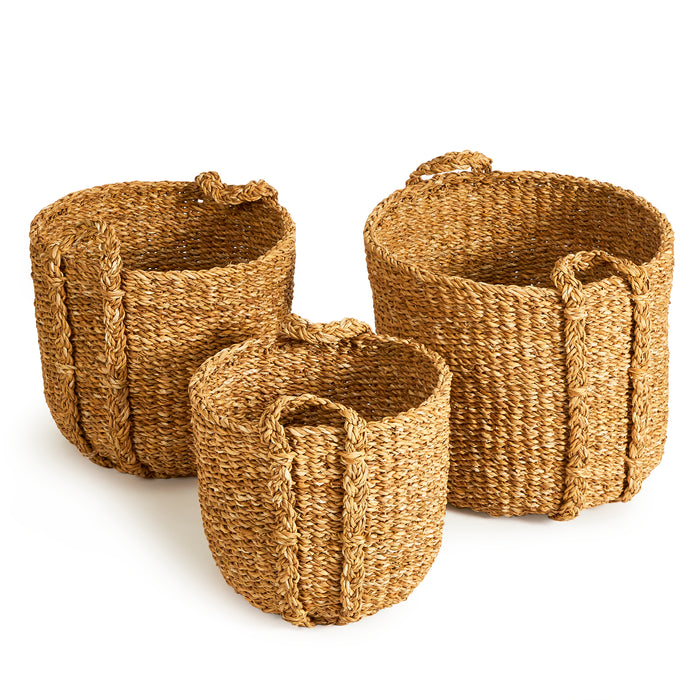 Three seagrass round baskets in natural tan, woven texture, looped handles, set of varying sizes against white background