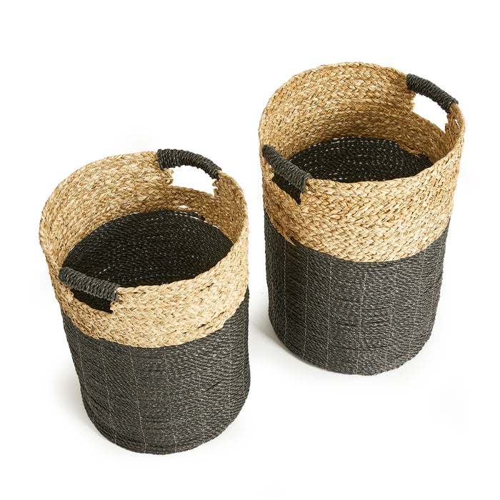 Two woven baskets in natural tan and dark gray with black braided handles, cylindrical shape, set of 2, against white