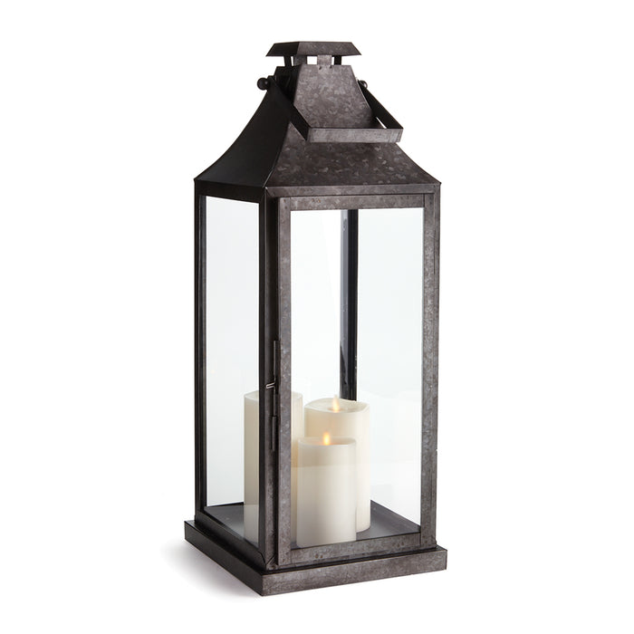 Barrington outdoor lantern with dark metal frame, glass panels, and three white candles inside on a square base.