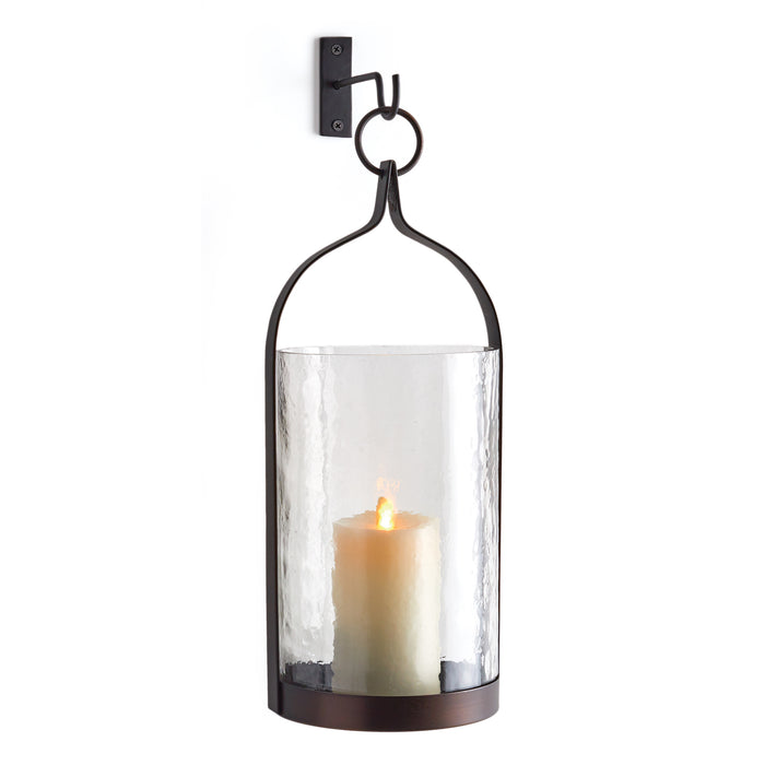 A clear glass lantern with a brown base and a black hanging bracket, featuring a candle inside.