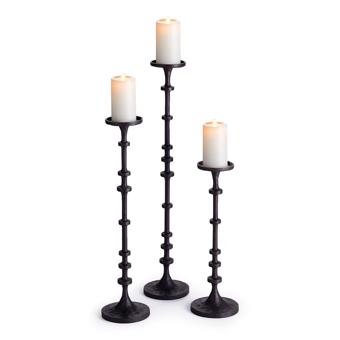 A set of three black aluminum candle stands, each with a candle on top, displayed against a white background.