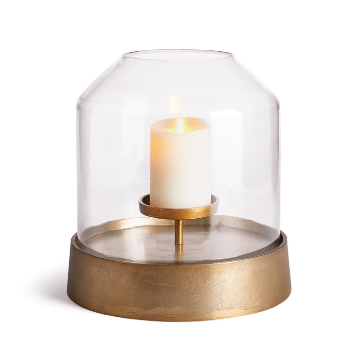 A cylindrical glass candle holder with a bronze-colored base and a lit candle inside.
