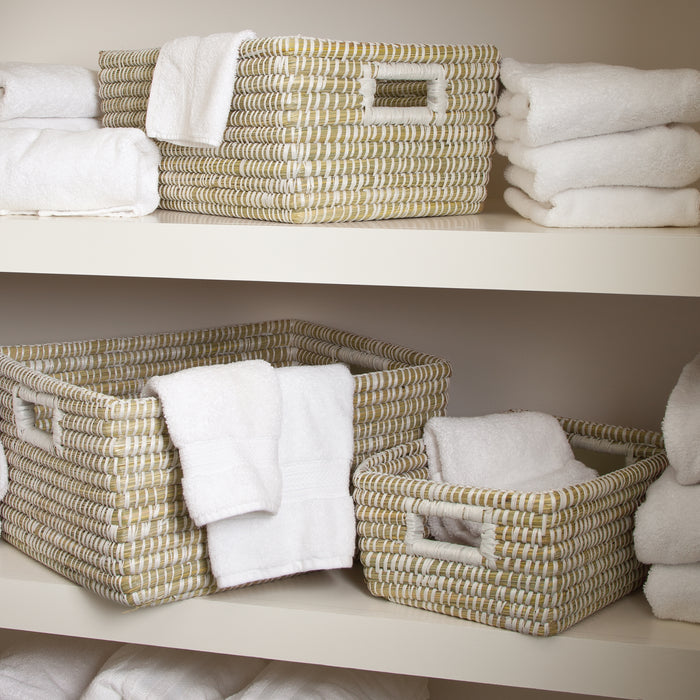 Three woven rectangular baskets with white towels, natural beige fibers on a shelf, clean and organized.