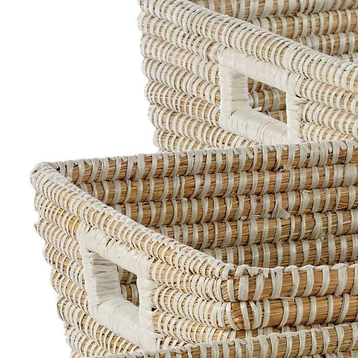 Set of three rectangular woven wicker baskets with light natural and white woven strands, stacked, handles visible.