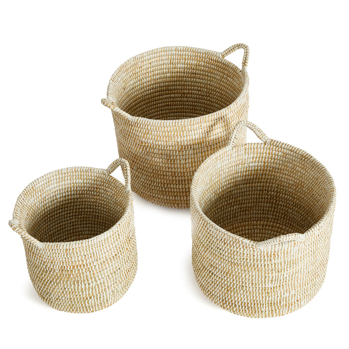 Set of three round woven baskets with handles in natural beige fibers, empty, on white background.