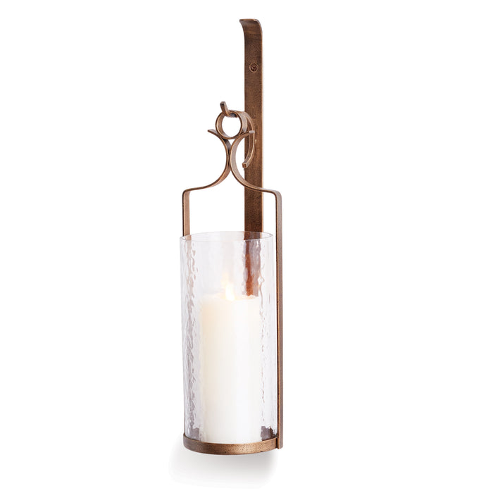 A wall-mounted candle sconce with a hammered glass shade and antique gold finish.
