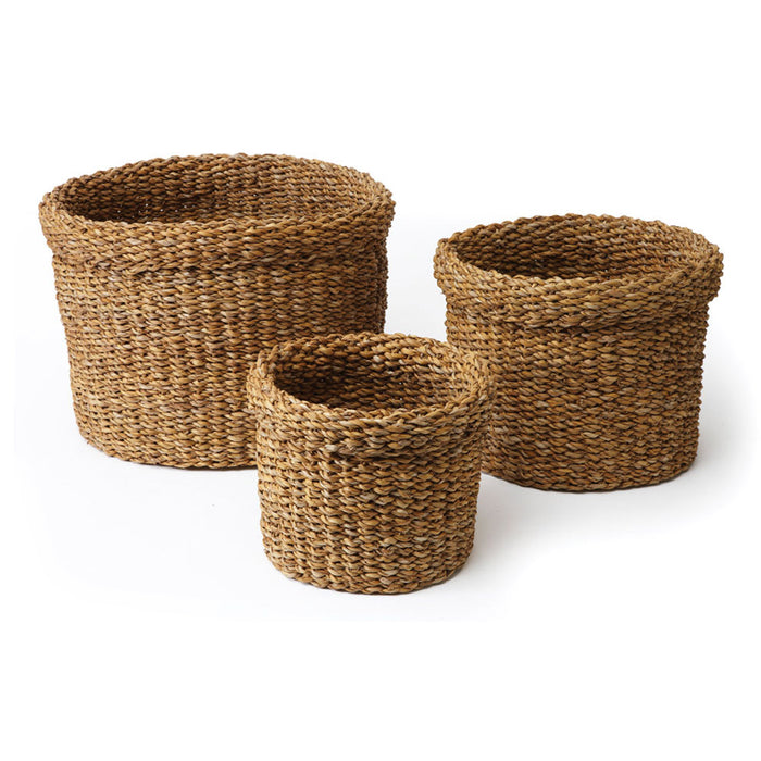 A set of three round seagrass baskets with cuffs, in beige color, woven fabric.