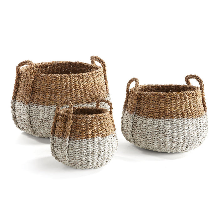 A set of three round seagrass baskets with handles, in different sizes, with a beige and brown color pattern.