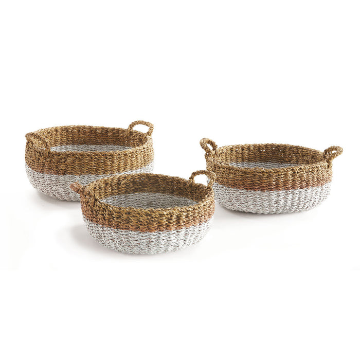A set of three round seagrass shallow baskets with handles, in varying shades of brown and beige, woven goods.