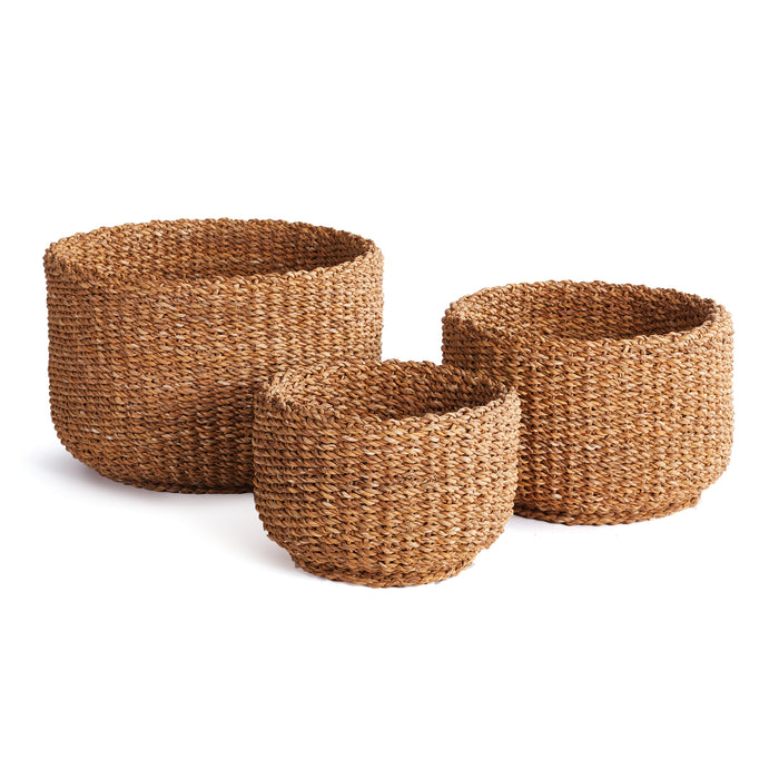 A set of three cylindrical seagrass baskets in brown color, with a textured weave pattern, displayed against a white background.