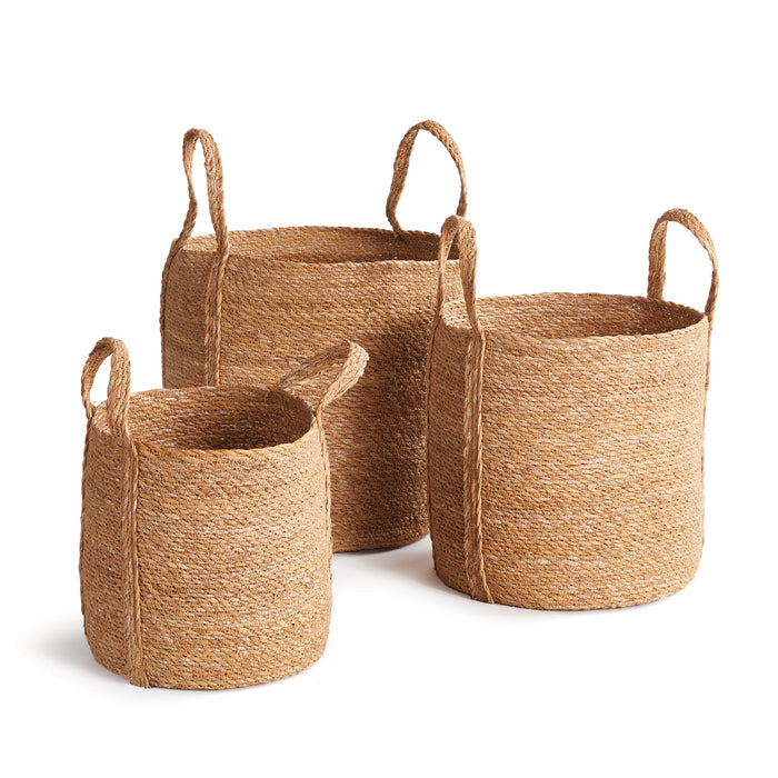 A set of three round seagrass baskets with long handles, displayed against a white background.