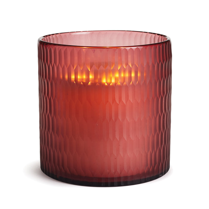 A deep red etched glass hurricane candle holder with a visible candle inside, reflecting on the curved surface.