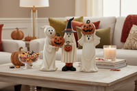 Three Halloween-themed figurines dressed as ghosts with pumpkins on a white background