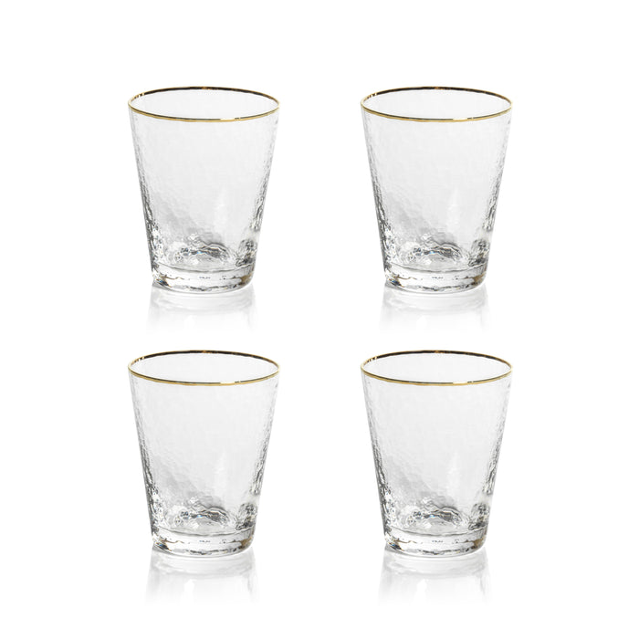 Four clear glass tumblers with gold rims on a white background