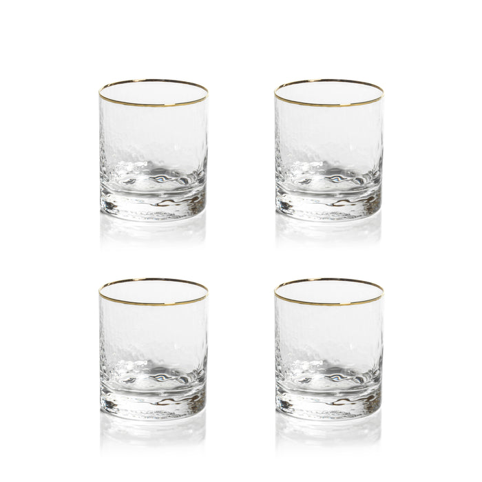 Four clear glasses with gold rims on a white background