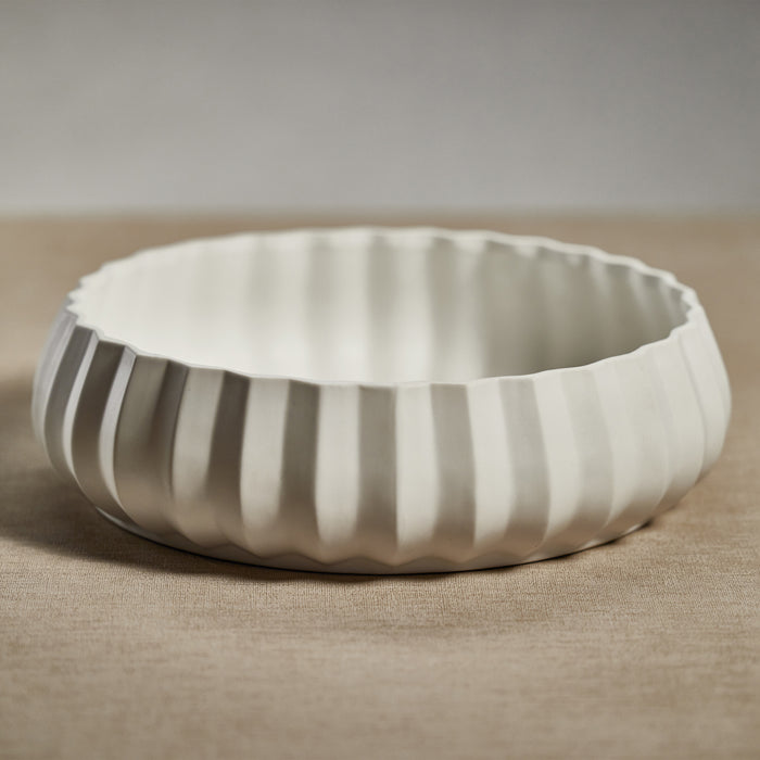 White ceramic bowl with ribbed texture on a beige surface