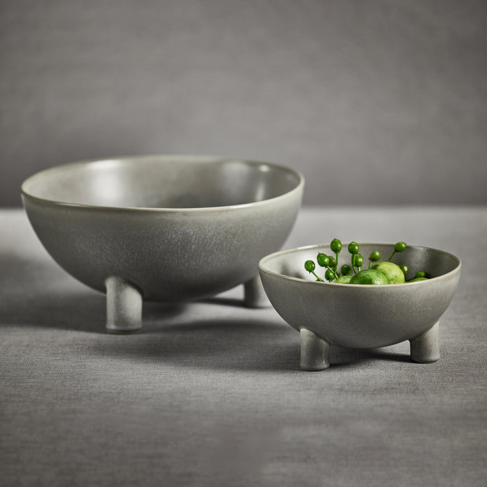 Two gray ceramic bowls on a gray surface with a blurred background