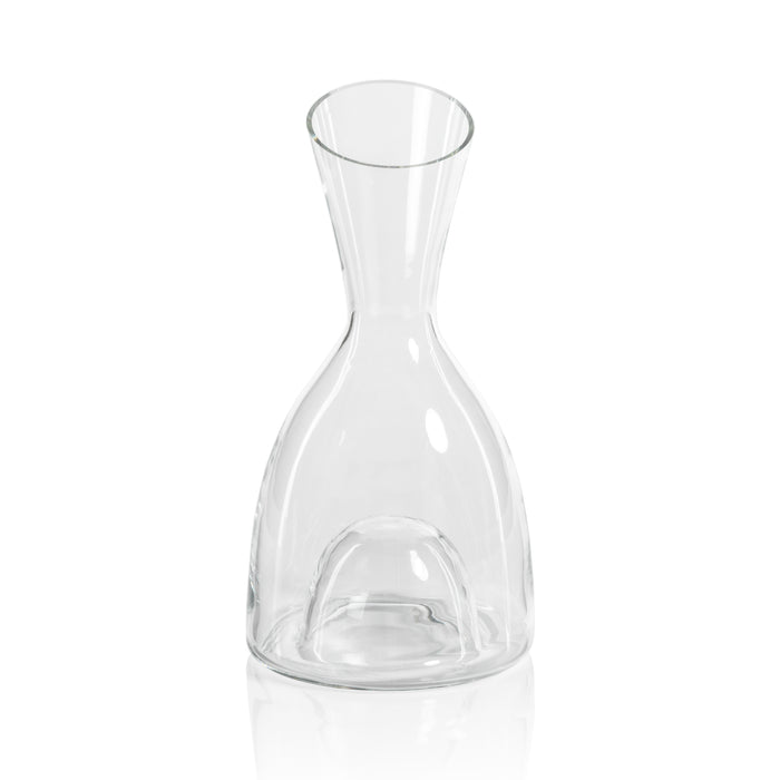 A clear glass wine decanter with a distinctive shape, featuring a narrow neck and a round base.