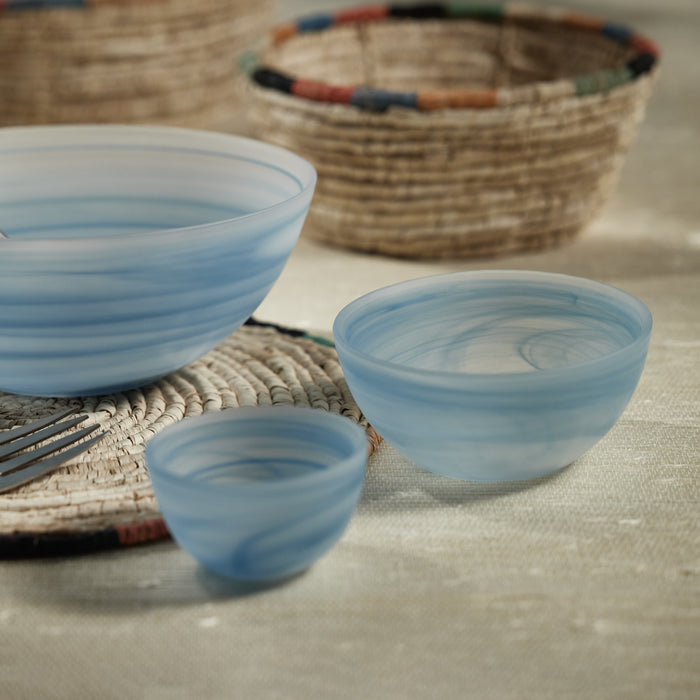 Set of blue ceramic bowls on a textured surface with a woven basket in the background.