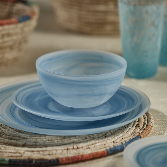 Set of blue ceramic dishes on a woven placemat with blurred background