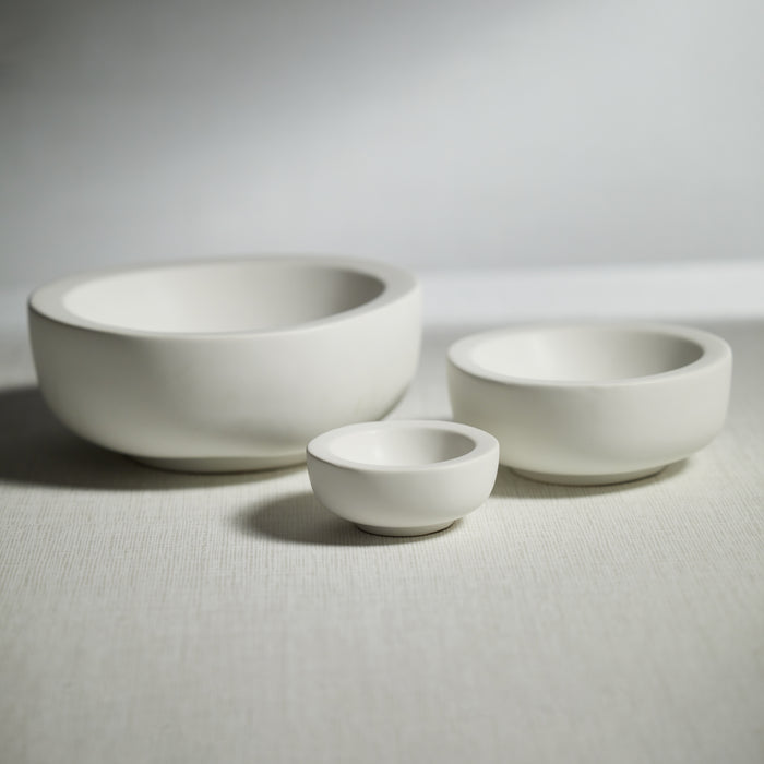 Three white ceramic bowls of different sizes on a light gray background