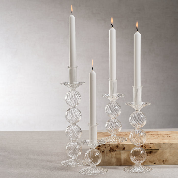Clear glass candle holders with white candles on a neutral background