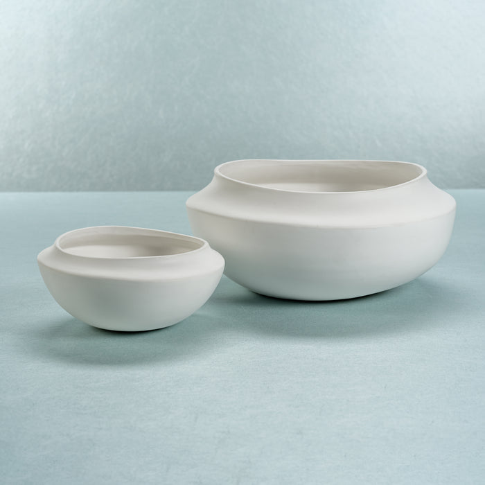 Two white ceramic bowls on a light blue surface with a light blue background
