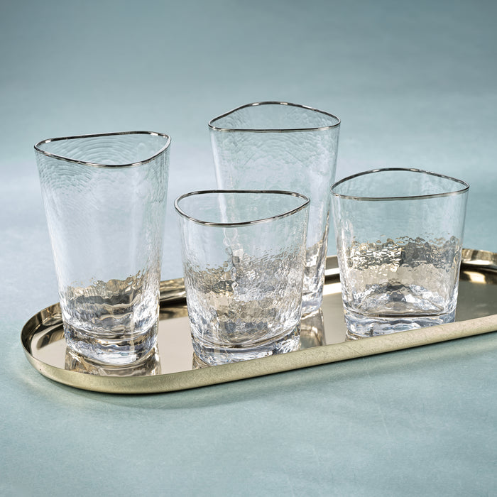 Four clear glasses with silver rims on a metallic tray against a light blue background