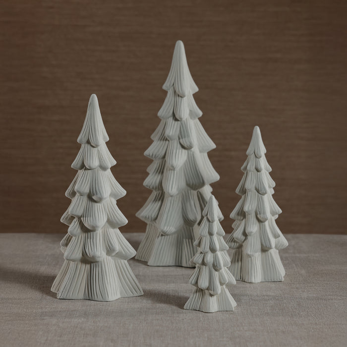 Set of four ceramic Christmas tree figurines on a neutral background