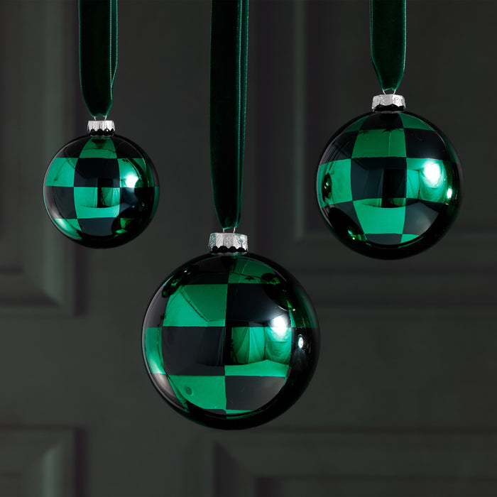 Three green and black checkered ornaments hanging against a dark background