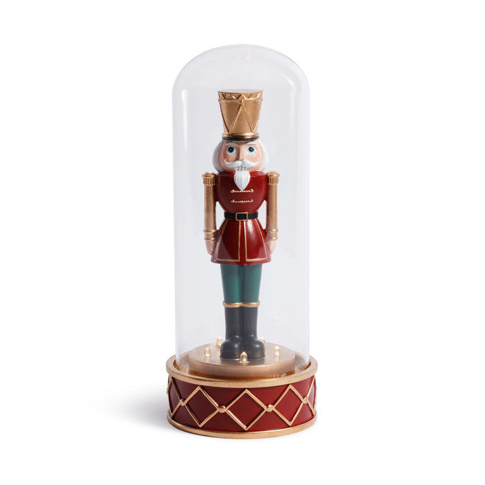 Decorative nutcracker figure under a glass dome on a white background