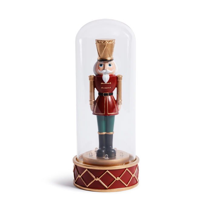 Nutcracker figurine under a glass dome on a white background