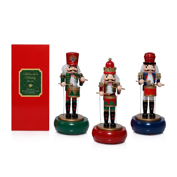 Three nutcracker figurines with a red gift box on a white background
