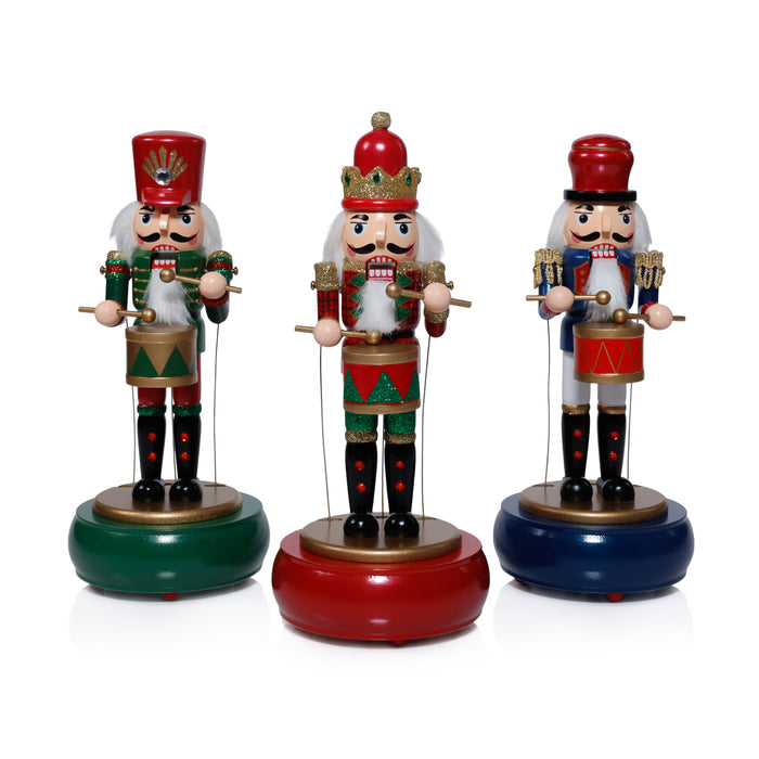 Three nutcracker figurines with red, green, and blue bases on a white background