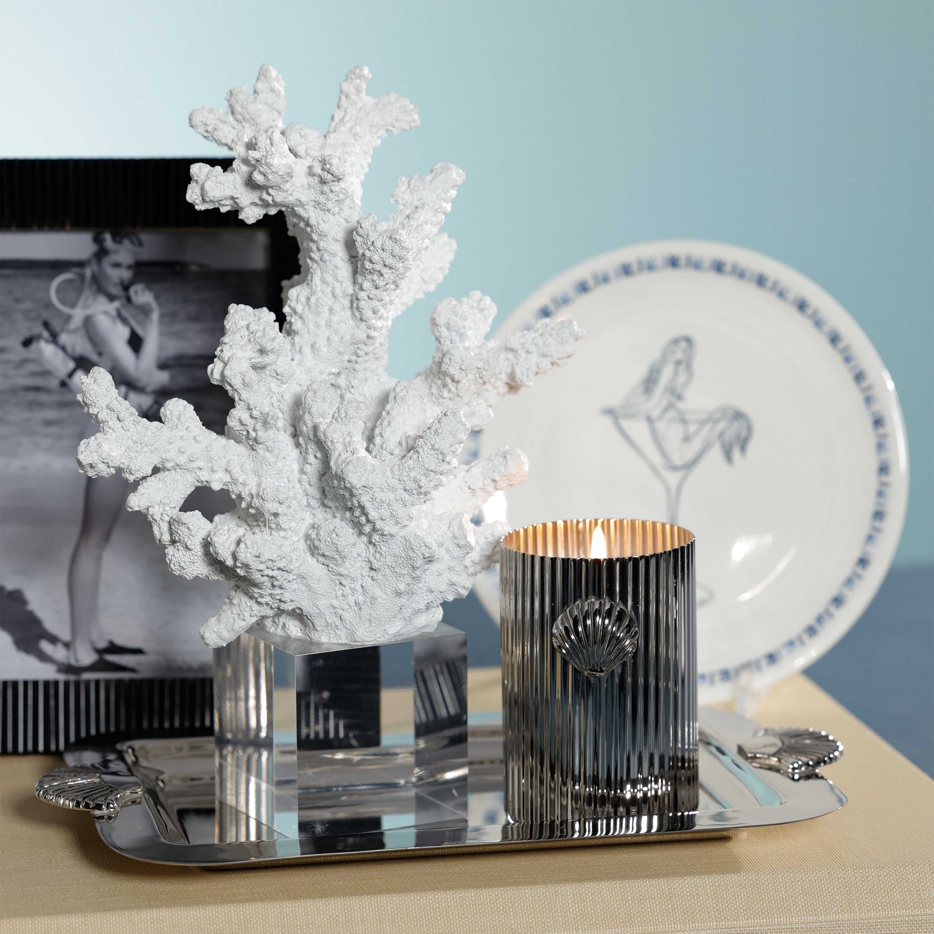 Decorative coral piece on a table with a candle and other items.