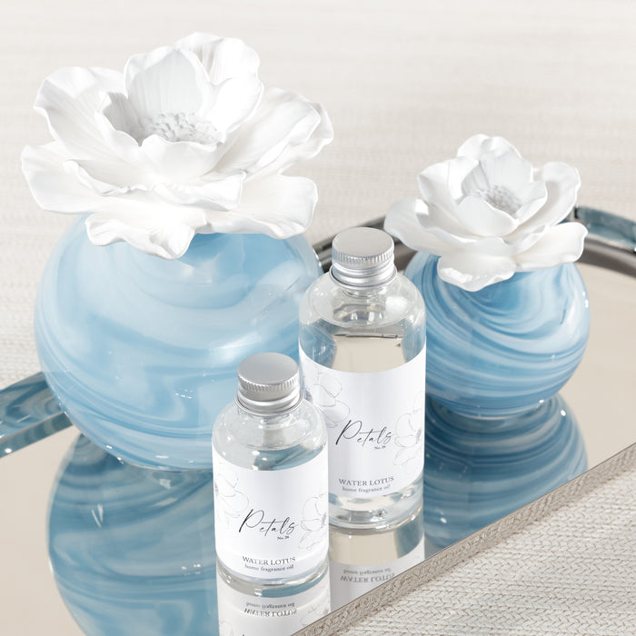 Set of blue and white marbled bottles with floral designs on a reflective surface.