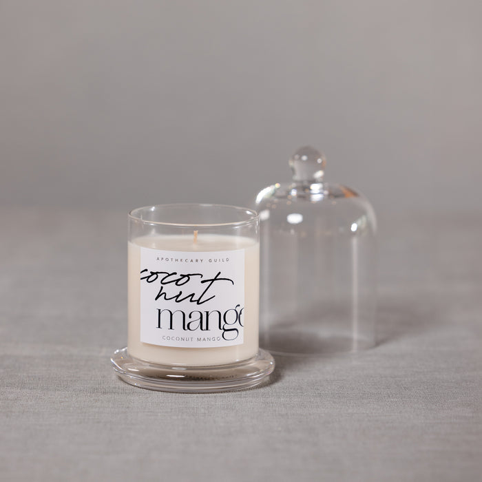 Candle with a label reading 'coconut mango' on a gray surface.