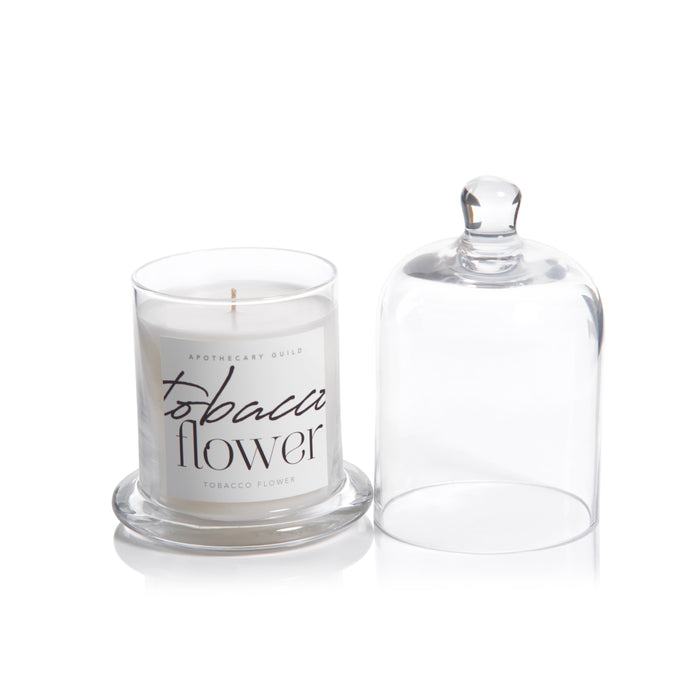 Candle labeled 'Tobacco Flower' with a clear glass lid on a white background