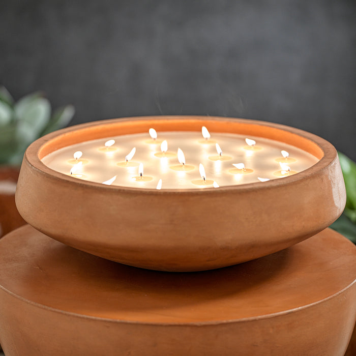 Round cement jar candle in warm terracotta tones, 20 wicks, cream wax, lit flames, on matching cement pedestal, soft blurred
