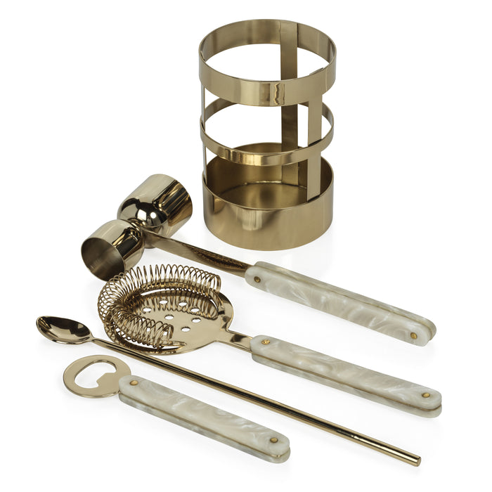 Set of gold cocktail tools including a jigger, strainer, spoon, and bottle opener on a white background.