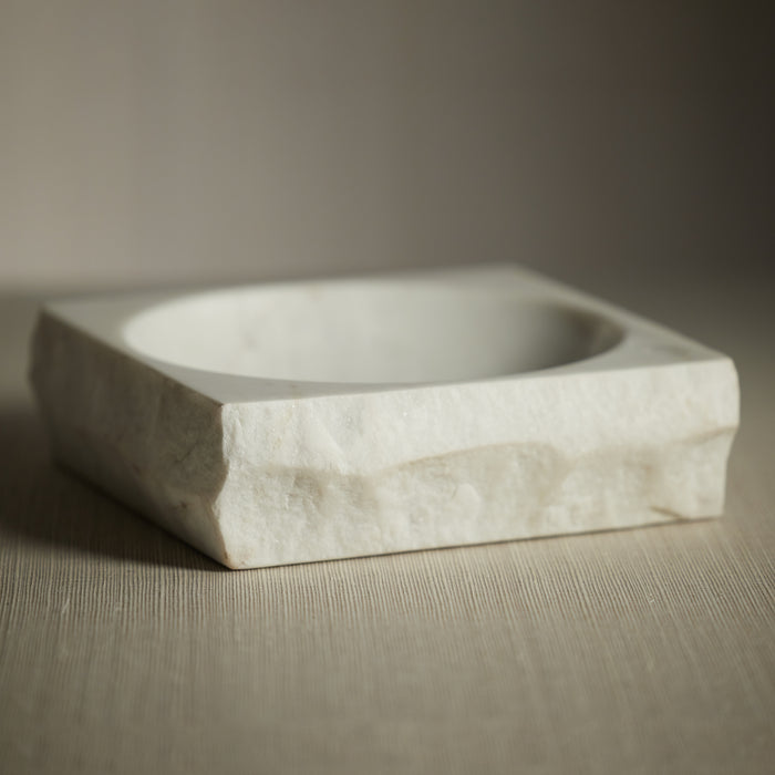 Hexagonal stone bowl on a textured surface with a neutral background