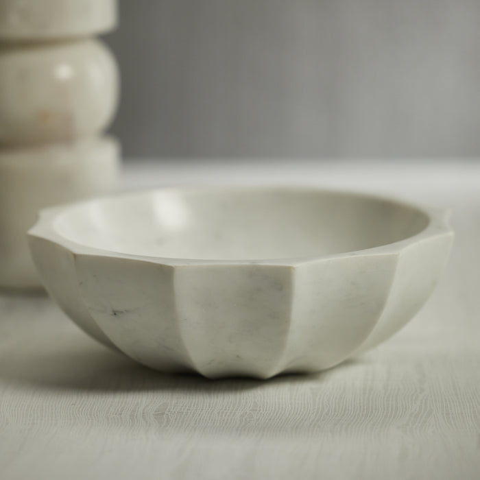 White marble scalloped edge bowl on light textured surface, soft shadow, neutral backdrop.