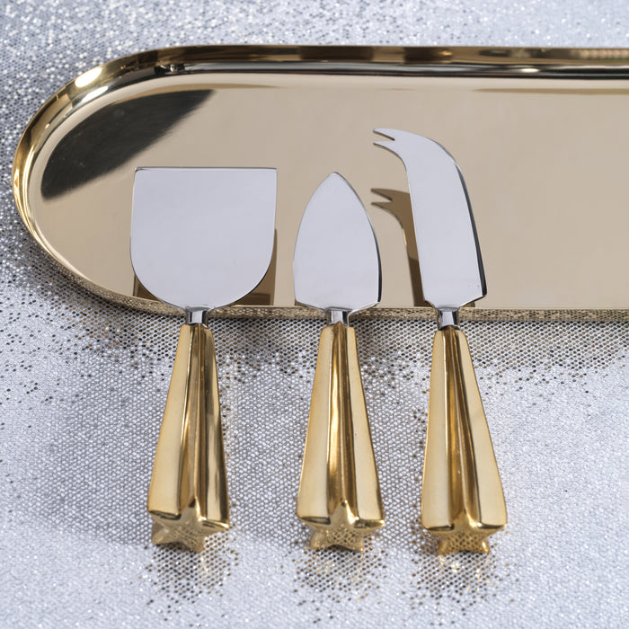 Set of three gold cheese knives on a reflective surface