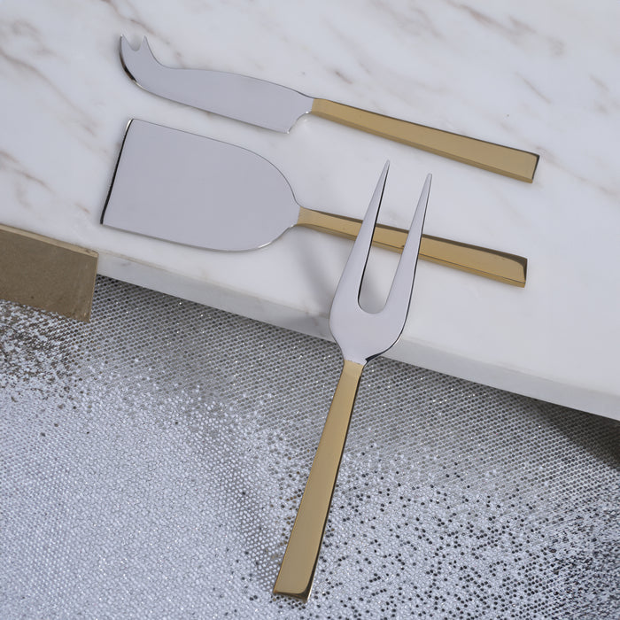 Set of silver cheese knives with gold handles on a marble surface