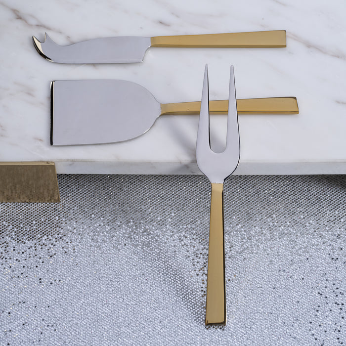 Stainless steel and gold cheese knife and fork on a textured surface