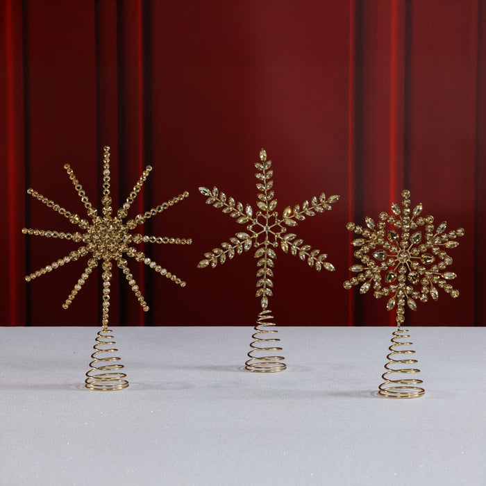 Three decorative gold trees on a white surface with a red curtain background