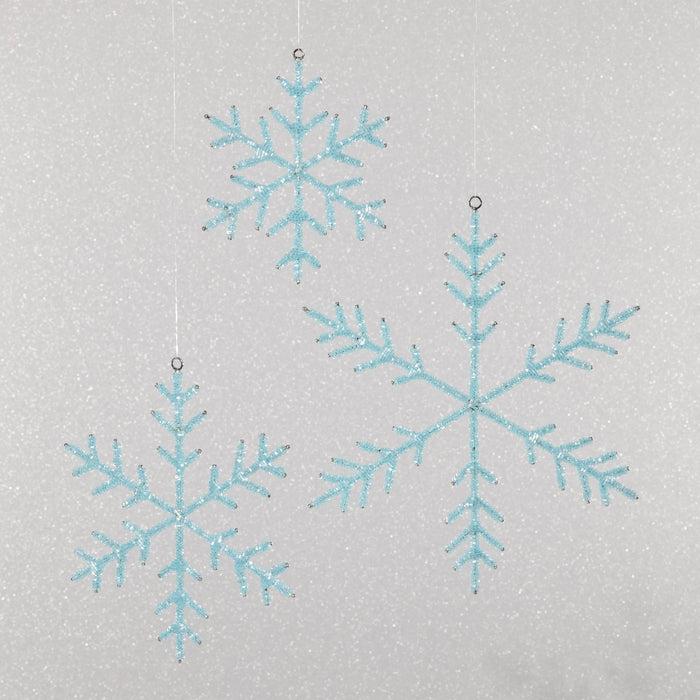 Three blue snowflake decorations on a light gray background